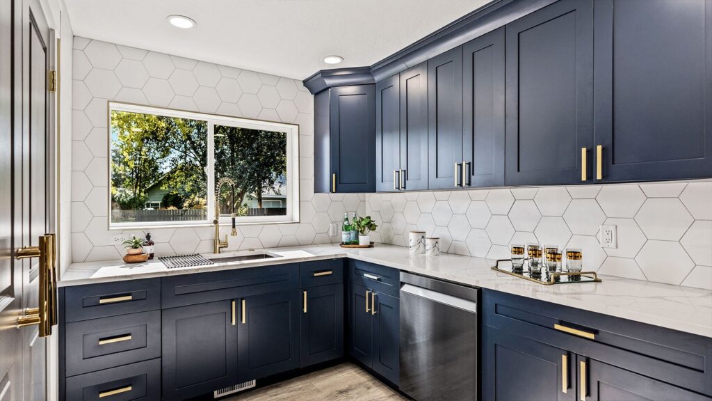 Beautiful Navy Blue Shaker Cabinets with white hexagon backsplash and white quartz countertops. The Blue Shaker Cabinetry has gold pulls on the doors and drawers.